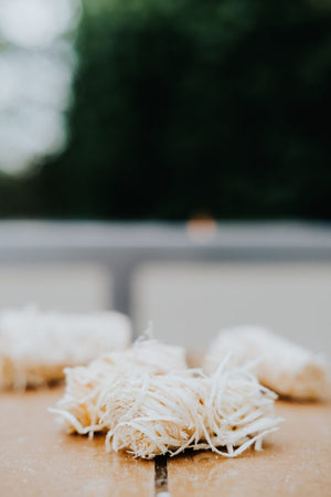 Close-up of individual Kasai Wood Wool Firelighters on wooden surface, highlighting their natural composition for easy ignition.