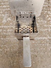 Metal smoker part with burn marks on concrete