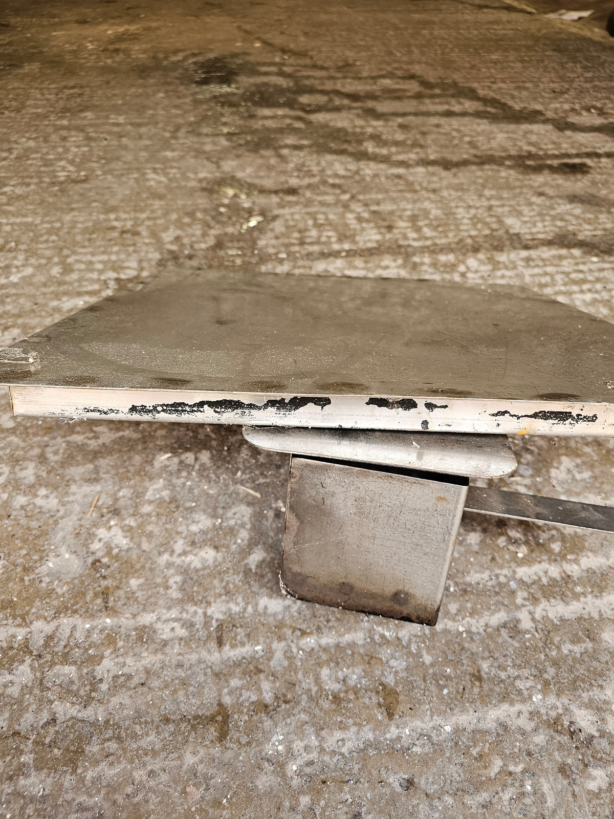 Close-up of metal smoker part on concrete floor