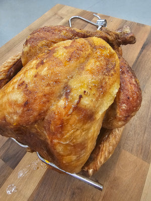 Whole roasted chicken with crispy golden skin prepared using the BBQ Bird Brine Kit, perfect for flavorful and juicy results.