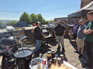 Group of men talking at outdoor BBQ with food and grill