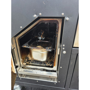 Used smoke generator chamber in Borniak Commercial Smoker showing residue and stainless steel tray after BBQ smoking session.