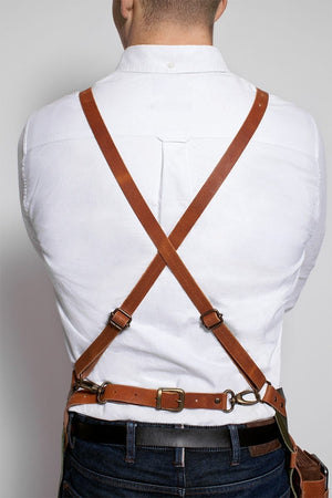 Back view of cross-strap leather BBQ apron worn over a white shirt, showing adjustable fit and secure buckle system for grilling ease.