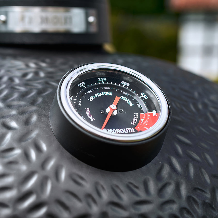 Monolith Avantgarde Kamado grill with built-in temperature gauge on textured black lid