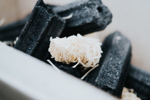 Close-up of a single Kasai Wood Wool Firelighter among charcoal pieces, showcasing its natural texture for efficient fire starting.