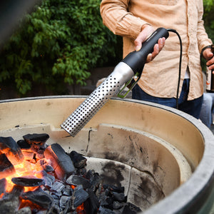 Man using Looftlighter Electric Grill & Fire Starter to ignite charcoal in a ceramic grill, demonstrating outdoor versatility and speed.