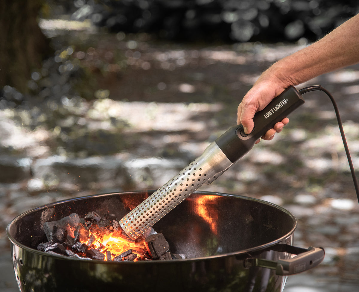 Electric charcoal starter with perforated metal tube igniting fire in a grill