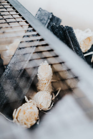 Multiple Kasai Wood Wool Firelighters arranged under grill with charcoal, ideal for BBQs and outdoor fire setups.