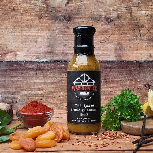 The Asado Apricot Chimichurri Sauce bottle on rustic wooden background with spices and herbs