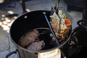 Pit Barrel All-Purpose Basket Hanger - FireFly Barbecue shown grilling vegetables vertically in a Pit Barrel Cooker next to burger patties.