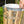 A silver metal bucket with a wire handle and a foil pan inside, being held by a hand outdoors.