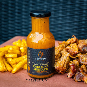 Firefly Carolina Mustard BBQ Sauce bottle placed beside pulled pork and seasoned fries, showcasing its sweet and tangy flavor pairing.