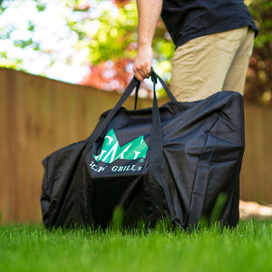 GMG Davy Crockett Tote Bag - FireFly Barbecue, portable grill cover with reinforced handles, shown in use on grassy outdoor setting.