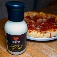 Peruvian Amarillo Chilli Aioli bottle next to pizza