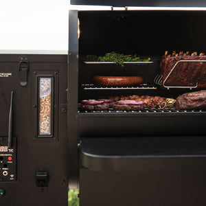GMG Prime 2.0 RACKT Backboard in action inside GMG Trek Cart, loaded with ribs, sausage, and vegetables on multi-tiered stainless steel racks.