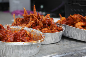 Trays of chicken wings coated in 7 Deadly Wings Hot Sauce, ready for a spicy food challenge or tasting event.