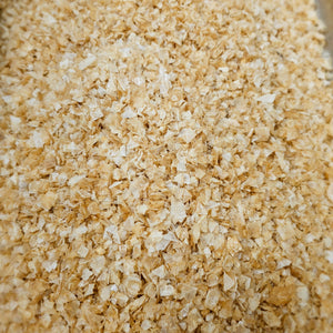 Close-up of loose Oak Smoked Greek Pyramid Salt flakes, showcasing their golden color and pyramid texture for culinary use.