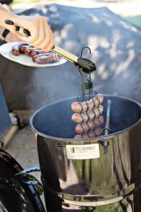 User placing sausages into Pit Barrel Cooker using the Pit Barrel Sausage, Hot Dog & Brat Hanger - FireFly Barbecue for vertical smoking.