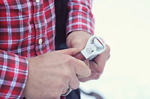 Person opening a bottle with Pit Barrel Ultimate Hook Tool - FireFly Barbecue, combining grilling accessory and bottle opener in one.