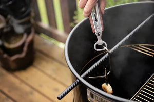 Pit Barrel Ultimate Tongs lifting a hook from a Pit Barrel Cooker, demonstrating its heavy-duty design for versatile grilling tasks.