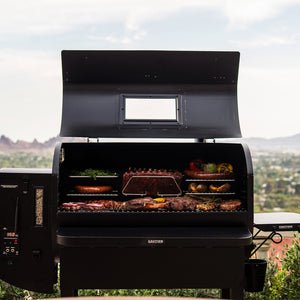 GMG Prime 2.0 RACKT Backboard installed in GMG Trek Cart, grilling assorted meats and vegetables with elevated racks for optimized cooking space.