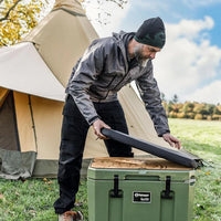 Man placing Petromax seat cushion on cool box during camping trip
