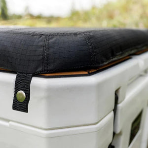 Close-up of Petromax Seat Cushion corner loop snapped onto white cool box, showing secure attachment detail.