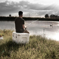 Man fishing by lake with Petromax 50L Cool Box