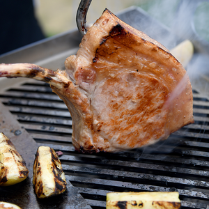 Grilled pork chop and vegetables on the Kasai Konro Plancha 50.50, demonstrating high-performance searing and grilling results.