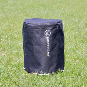 Kindling Cracker Hammer Cover placed on grass, featuring weather-resistant material and drawstring closure for outdoor tool storage.
