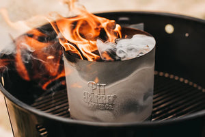 Flames rising from Pit Barrel Chimney Starter during ignition, emphasizing fast and fluid-free charcoal lighting process.