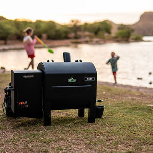 TREK PRIME 2.0 Pellet Grill by Green Mountain Grills set up lakeside, showcasing its portability and outdoor cooking versatility.