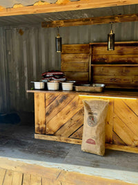 Wooden outdoor kitchen with bags of lump charcoal and grilling accessories