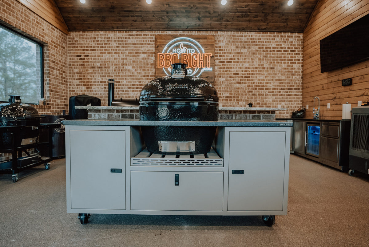 Indoor kitchen with brick wall, neon BBQ sign, and Primo grill