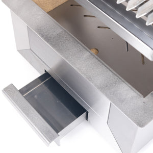 Ash drawer of the Bertha Asado Grill Small pulled out, highlighting easy cleanup and maintenance for outdoor grilling convenience.