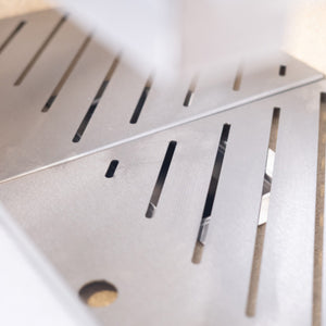 Detailed look at the slotted fire tray inside the Bertha Asado Grill Medium, designed for optimal airflow and heat distribution.