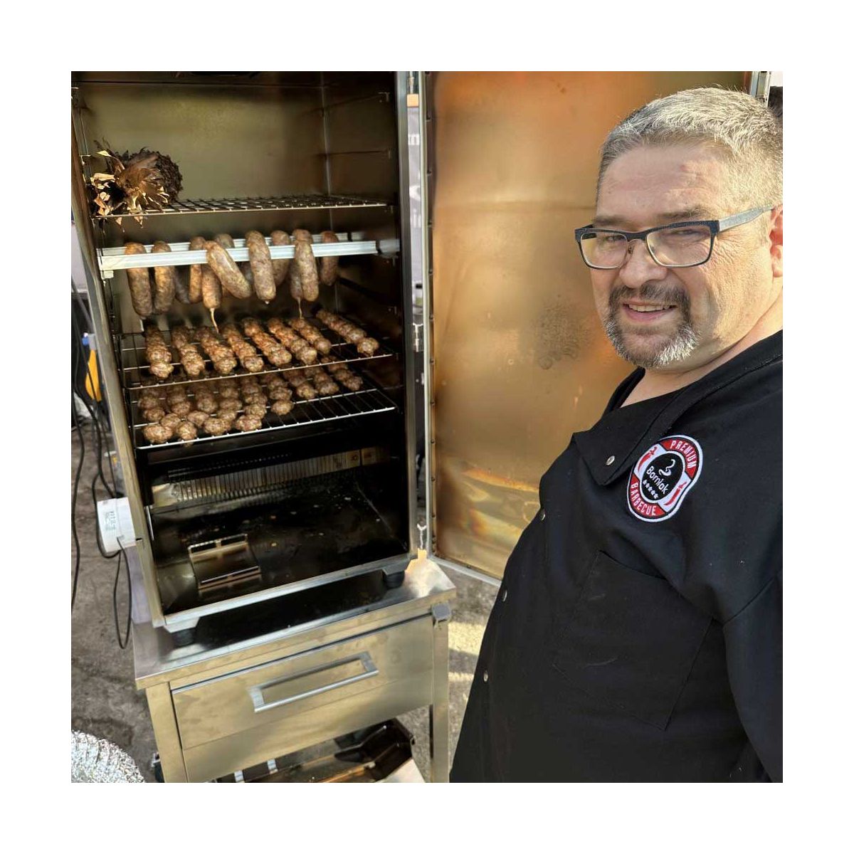 Man grilling sausages in commercial smoker with food dehydrator