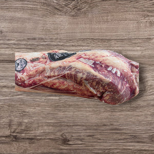 Side view of Jack's Creek grain-fed Black Angus brisket, highlighting thick marbling and vacuum-sealed freshness on wooden surface.