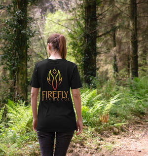 Back view of woman in forest wearing black Firefly Barbecue T-Shirt with flame logo, eco-friendly BBQ-themed women's apparel.
