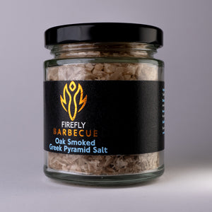 Close-up of Oak Smoked Greek Pyramid Salt in a clear jar with visible salt flakes, ideal for enhancing flavor in gourmet dishes.