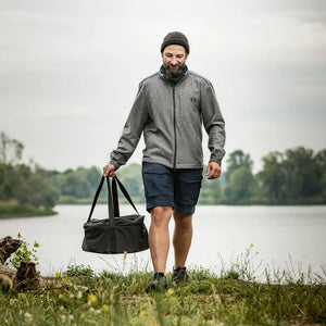 Man carrying Petromax Transport Bag for Dutch Oven and Atago Stove, showcasing portability and convenience for outdoor grilling adventures.