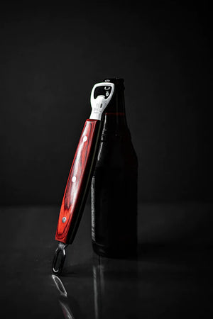 Pit Barrel Ultimate Hook Tool - FireFly Barbecue leaning on a beer bottle, highlighting its dual function as a bottle opener.