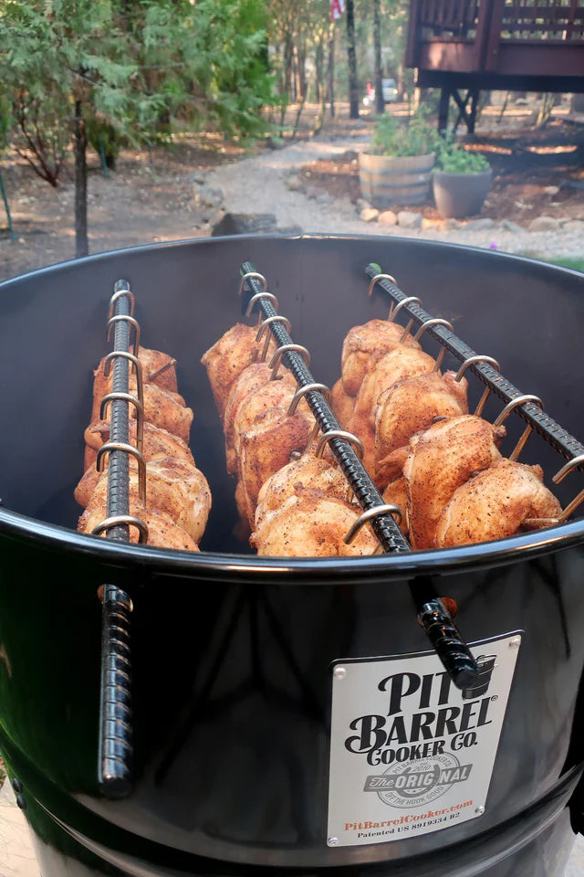 Close-up of Pit Barrel Cooker with cooked chicken on rotisserie rods