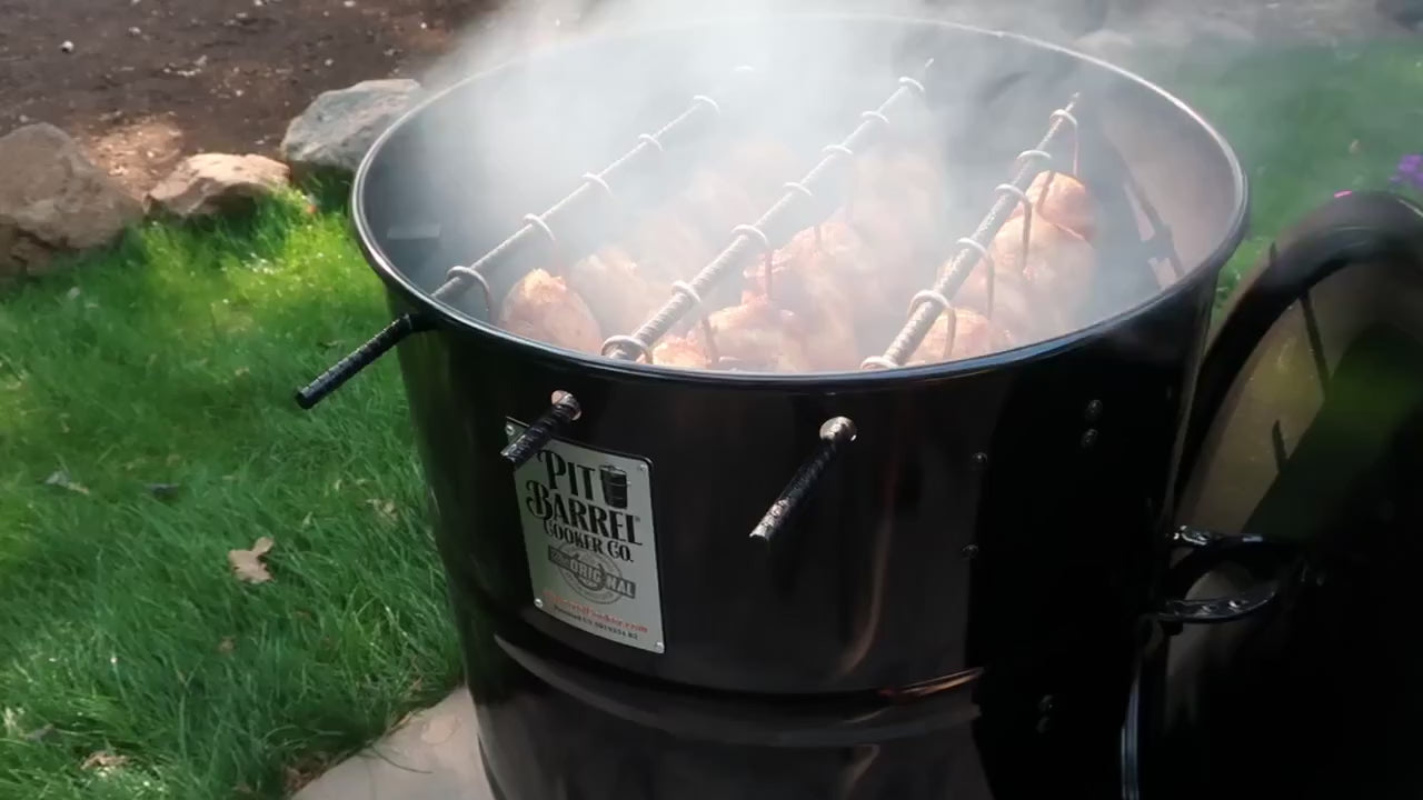 Pit Barrel Cooker Prime Package - 22.5" PBX in action outdoors, smoking poultry with visible smoke and efficient 360º Heat Dynamics.