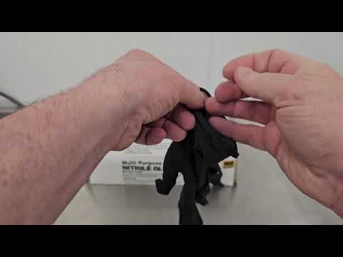 Hands stretching black nitrile barbecue glove to demonstrate tear resistance and flexibility for industrial and food handling tasks.