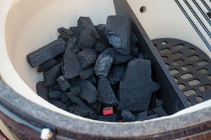 Charcoal-filled firebox of Primo Oval JR 200 Ceramic BBQ Grill, designed for efficient heat retention and smoking performance.