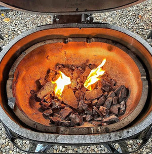 Lit charcoal inside Primo Grills Oval LG 300 fire box. Demonstrates efficient heat retention and ceramic insulation.