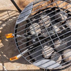 Close-up of Petromax Grilling Grate over hot briquettes in Atago grill, highlighting stainless steel durability and grilling efficiency.