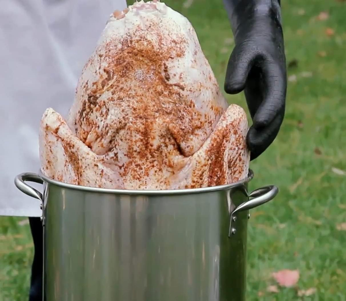 RAPICCA BBQ Gloves used for safely placing seasoned turkey into deep fryer, perfect for outdoor cooking.
