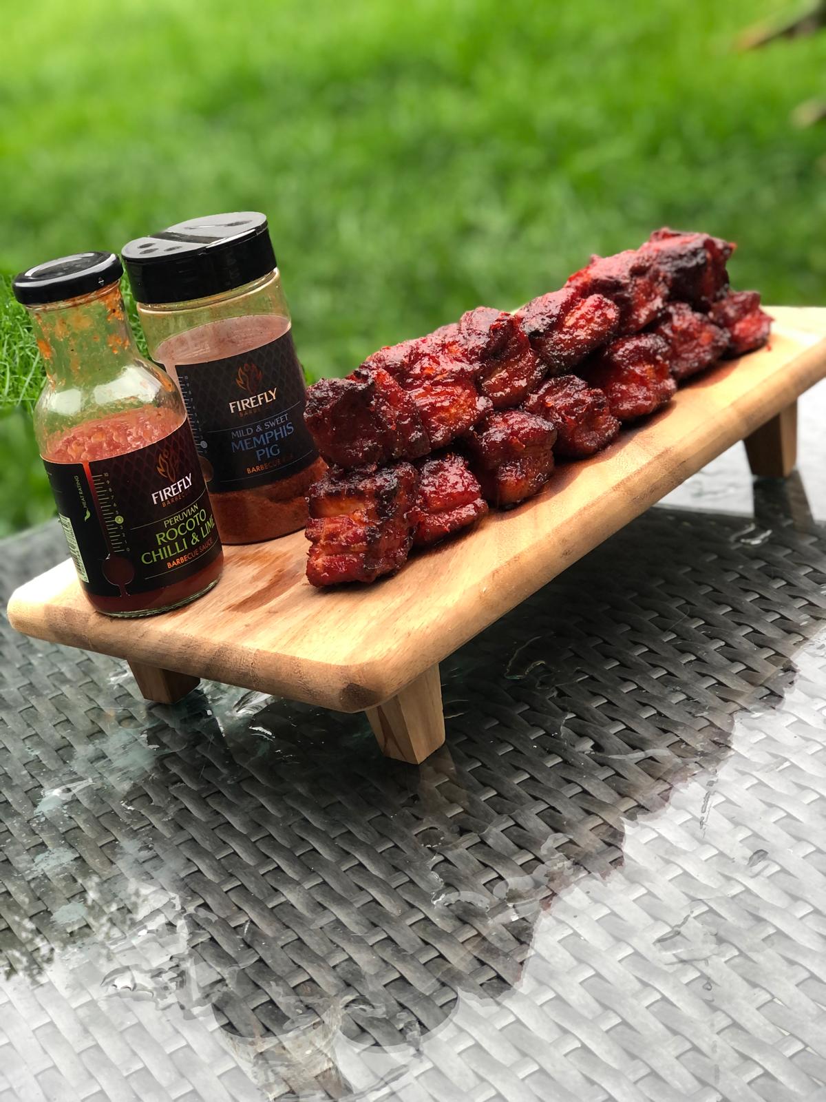 Barbecue ribs glazed with Firefly BBQ Peruvian Rocoto Chilli & Lime Sauce, served with Firefly Memphis BBQ rub on outdoor table.